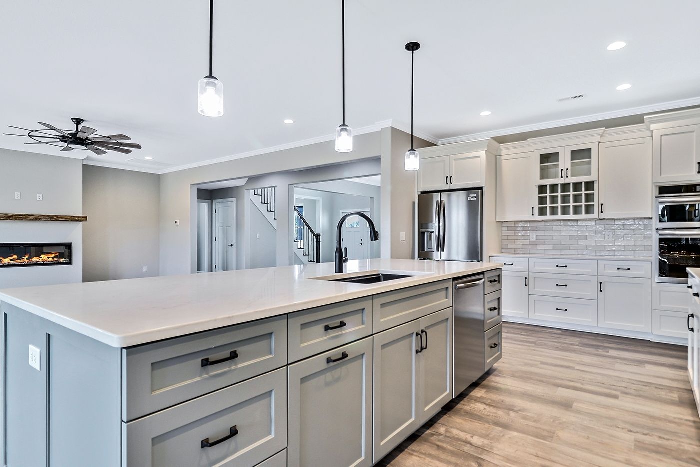 A kitchen with white cabinets , stainless steel appliances , and a large island.
