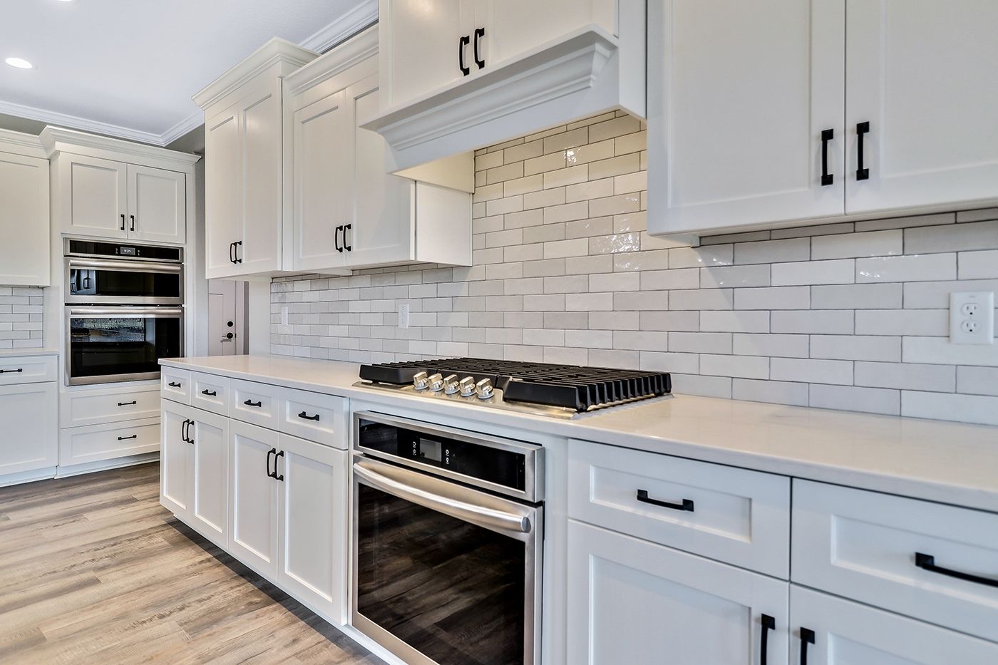 A kitchen with white cabinets , stainless steel appliances , and a stove top oven.