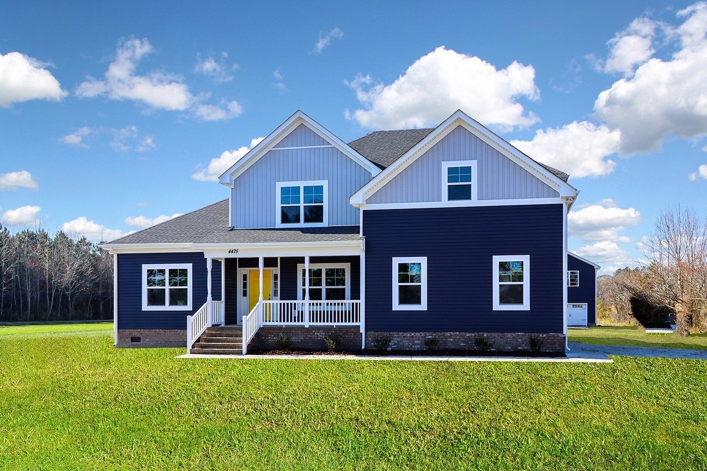 A blue and white house is sitting on top of a lush green field.