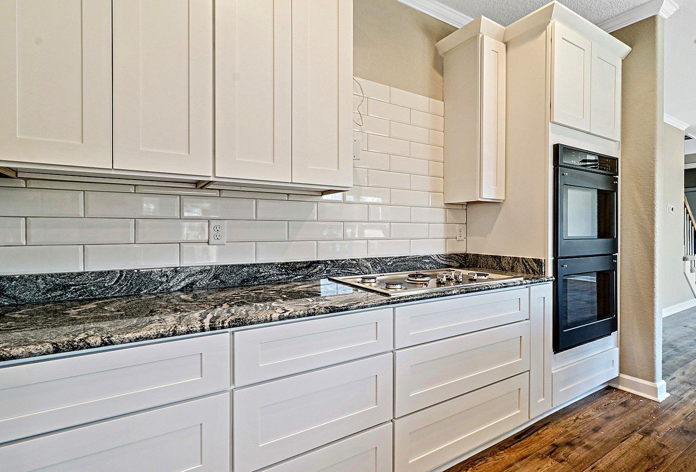 A kitchen with white cabinets and granite counter tops.
