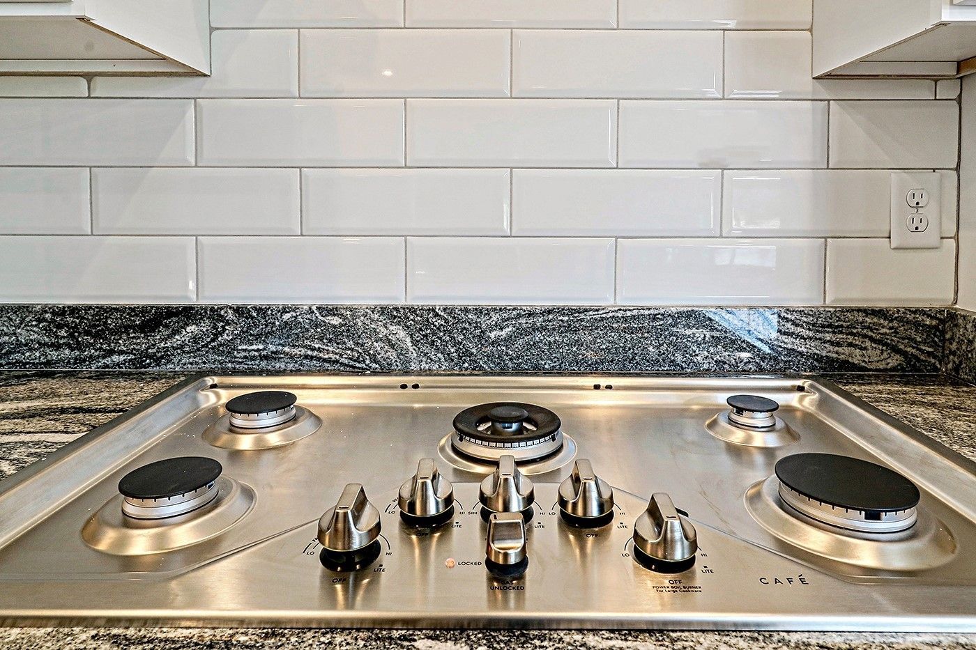 A stainless steel gas stove is sitting on top of a granite counter in a kitchen.