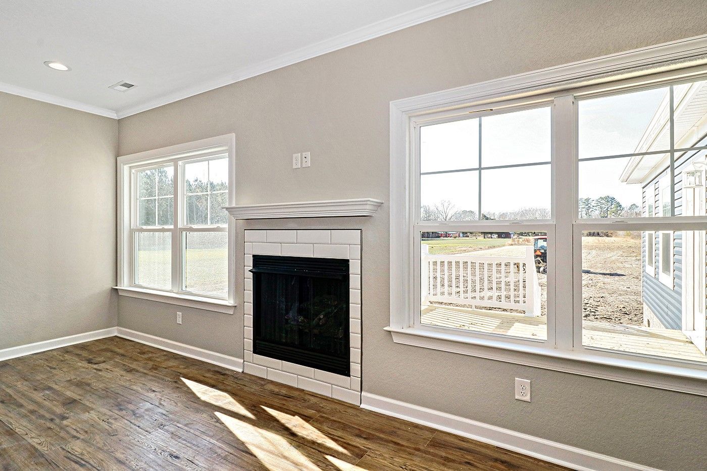 An empty living room with a fireplace and lots of windows.