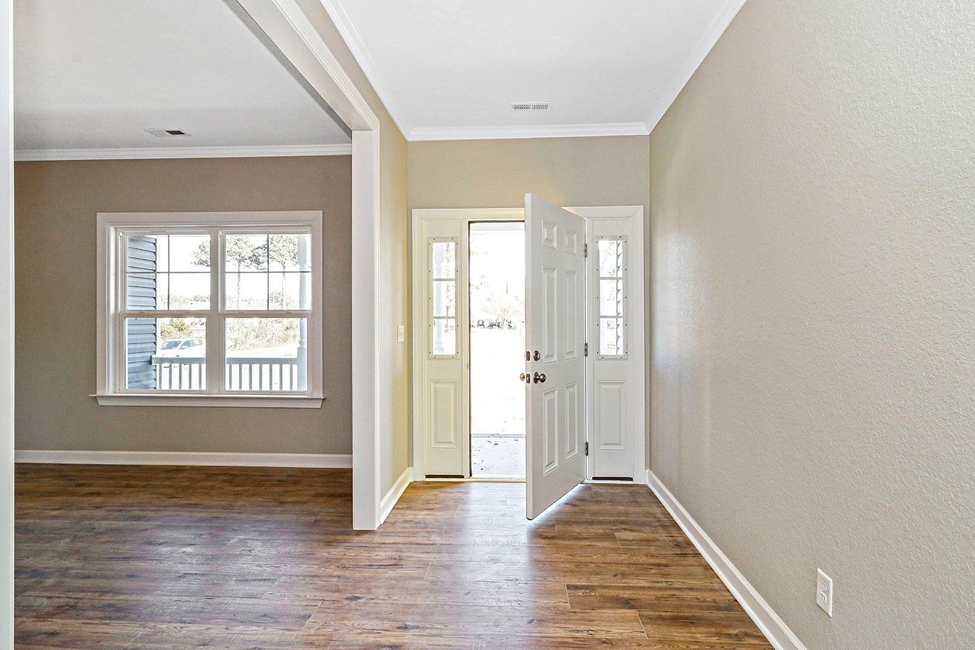 An empty room with hardwood floors and a white door.
