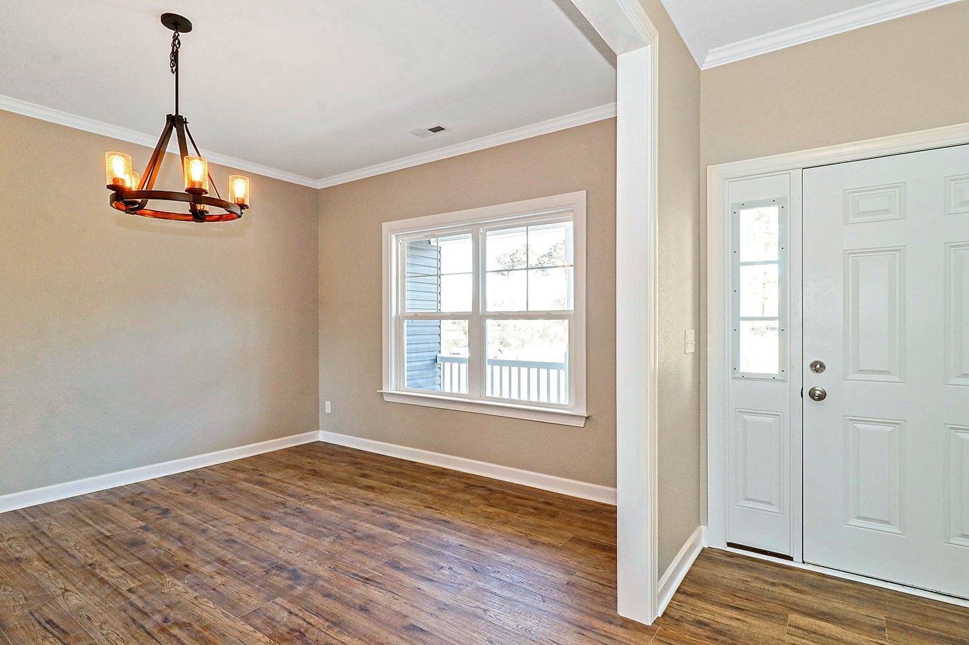 An empty dining room with hardwood floors and a chandelier.