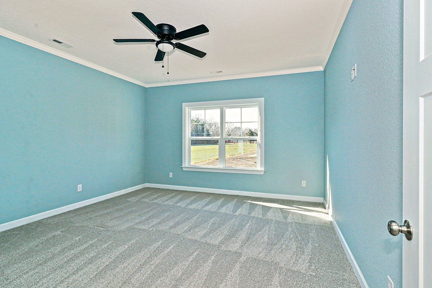 An empty bedroom with blue walls and a ceiling fan.