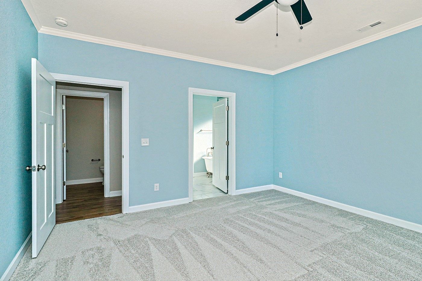 An empty bedroom with blue walls and a ceiling fan.