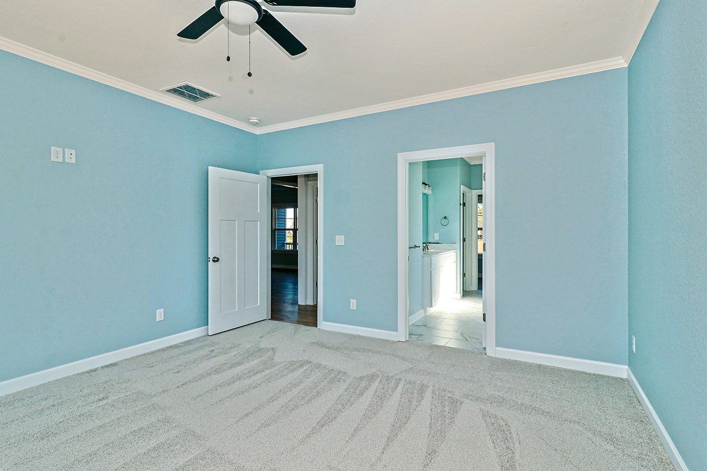 An empty bedroom with blue walls and a ceiling fan.