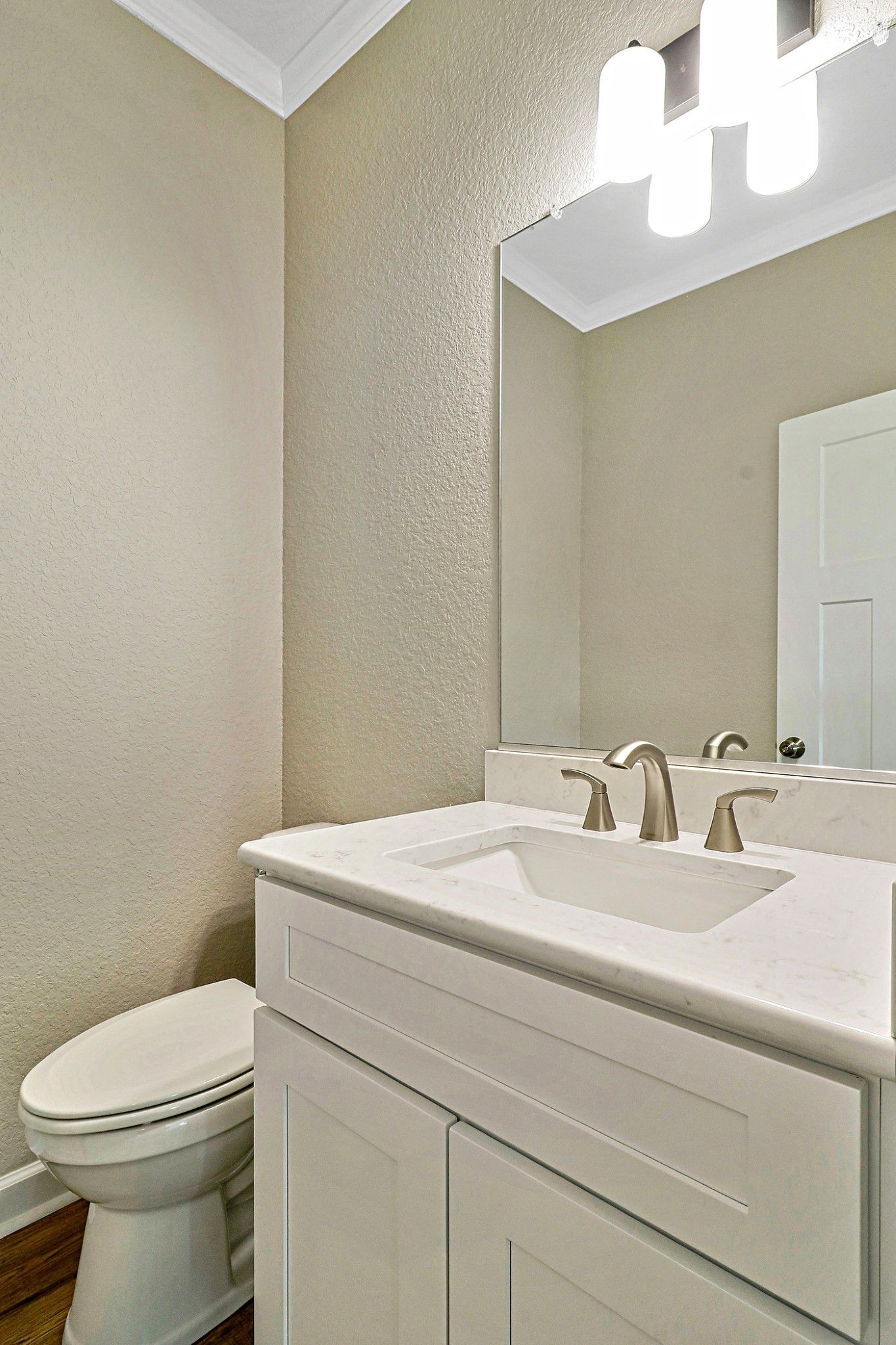 A bathroom with a toilet , sink and mirror.