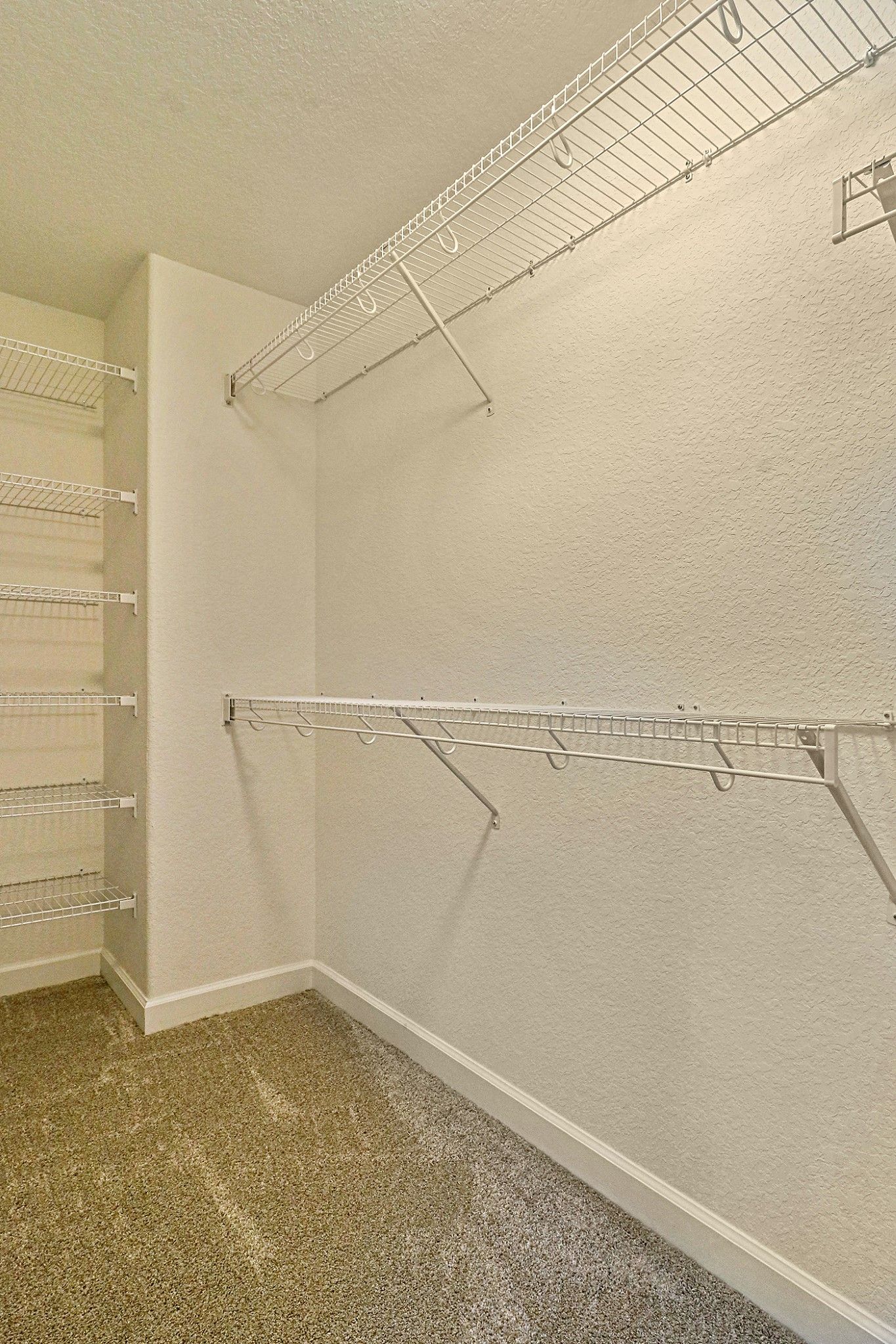 A walk in closet with lots of shelves and clothes racks.