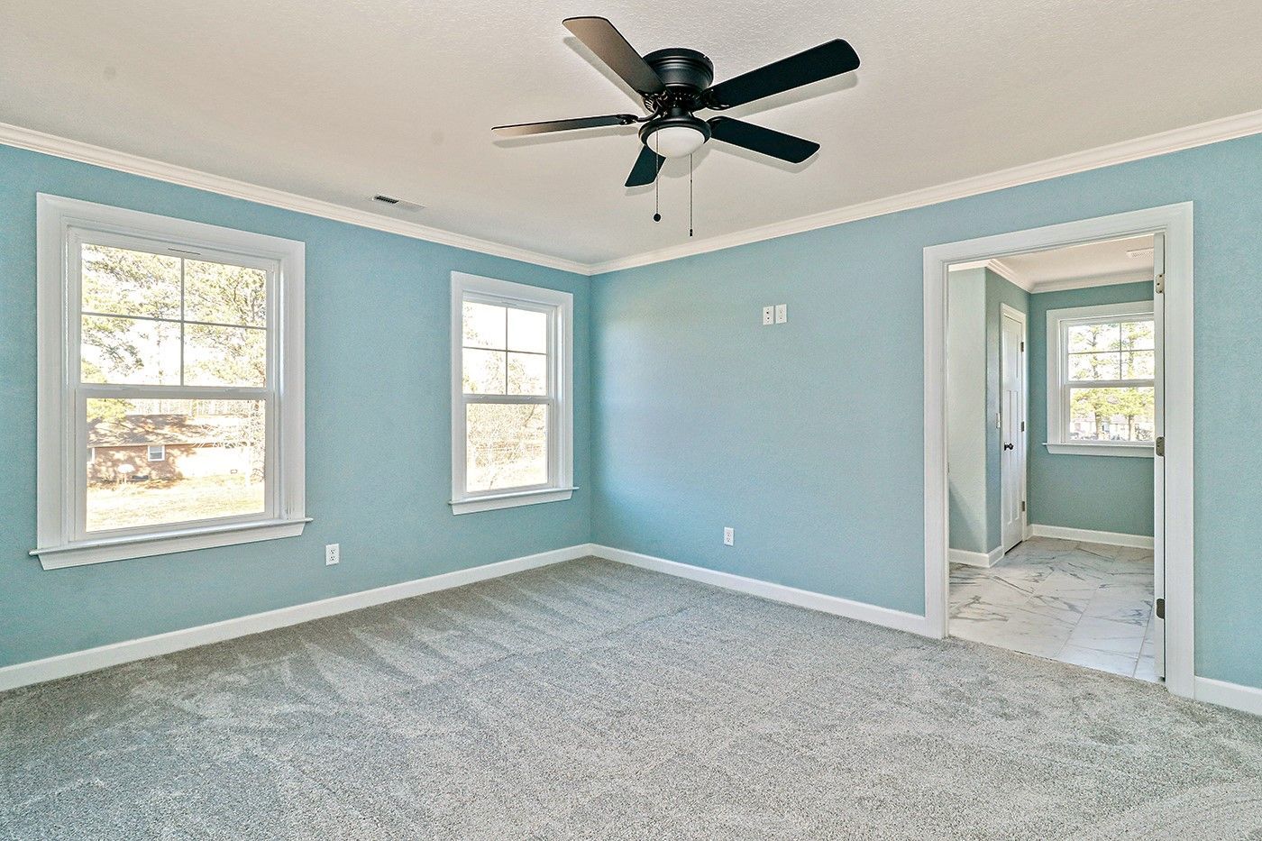 An empty bedroom with blue walls and a ceiling fan.