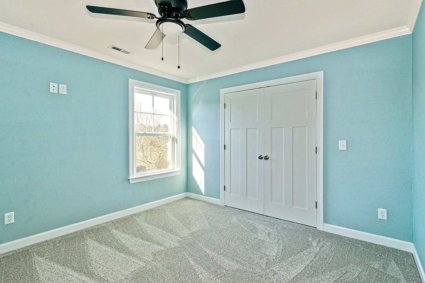An empty bedroom with blue walls and a ceiling fan.