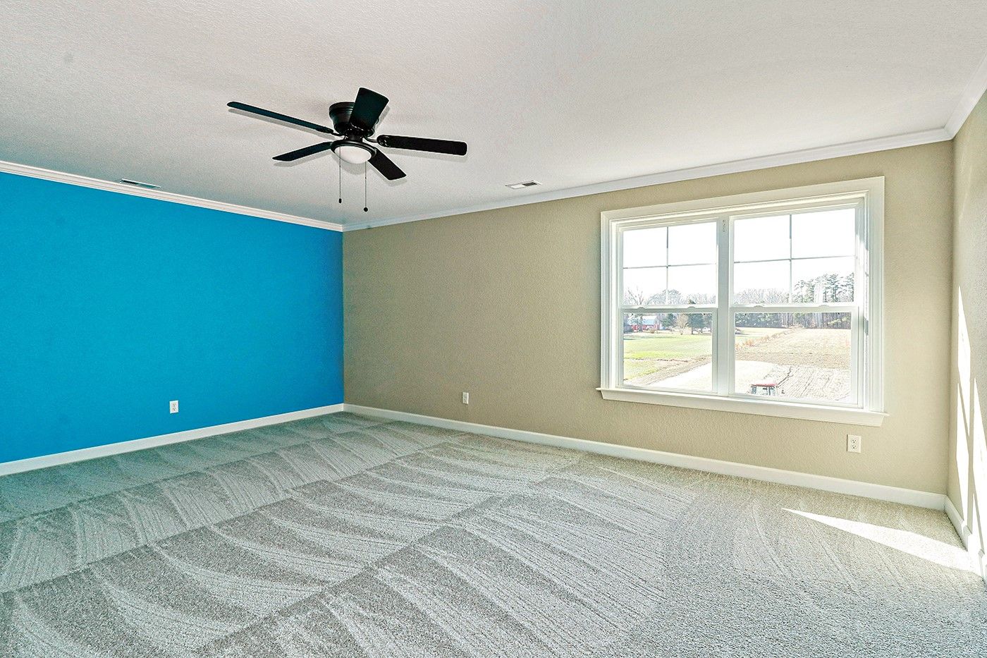 An empty room with blue walls and a ceiling fan.