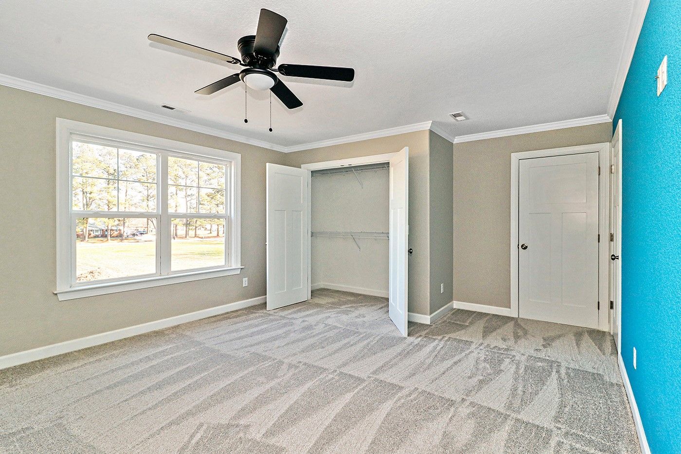 An empty bedroom with a ceiling fan and a blue wall.