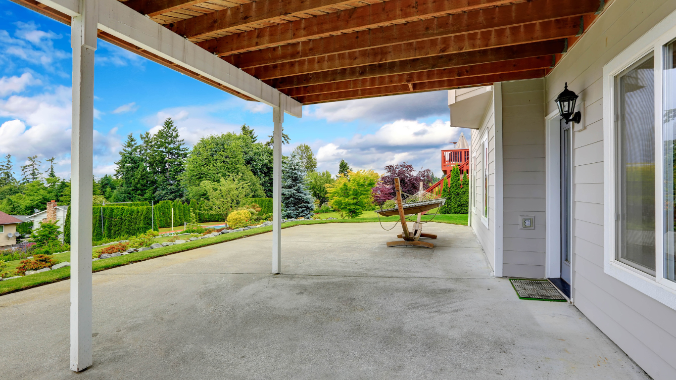 An empty patio with a wooden roof and a table underneath it.