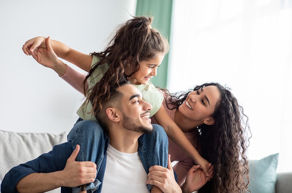Family of 3 with child on fathers shoulders, happy together