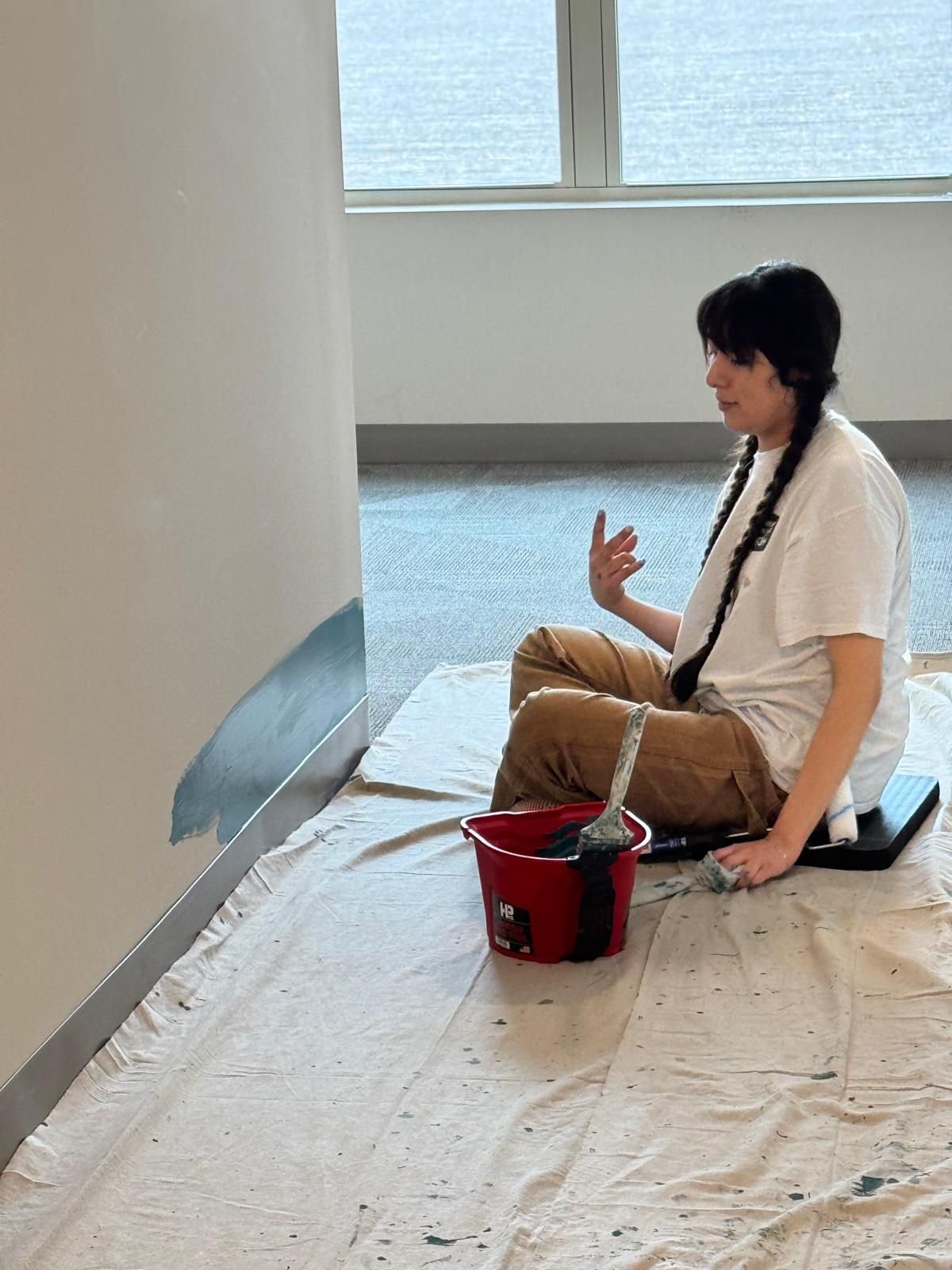 A person is painting a wall with a paint roller.