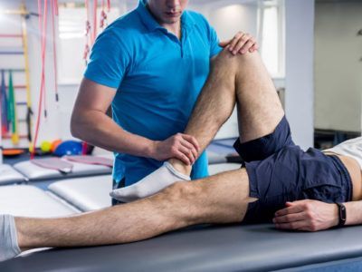 Physiotherapist examining a patient's leg on a treatment table in a clinic.