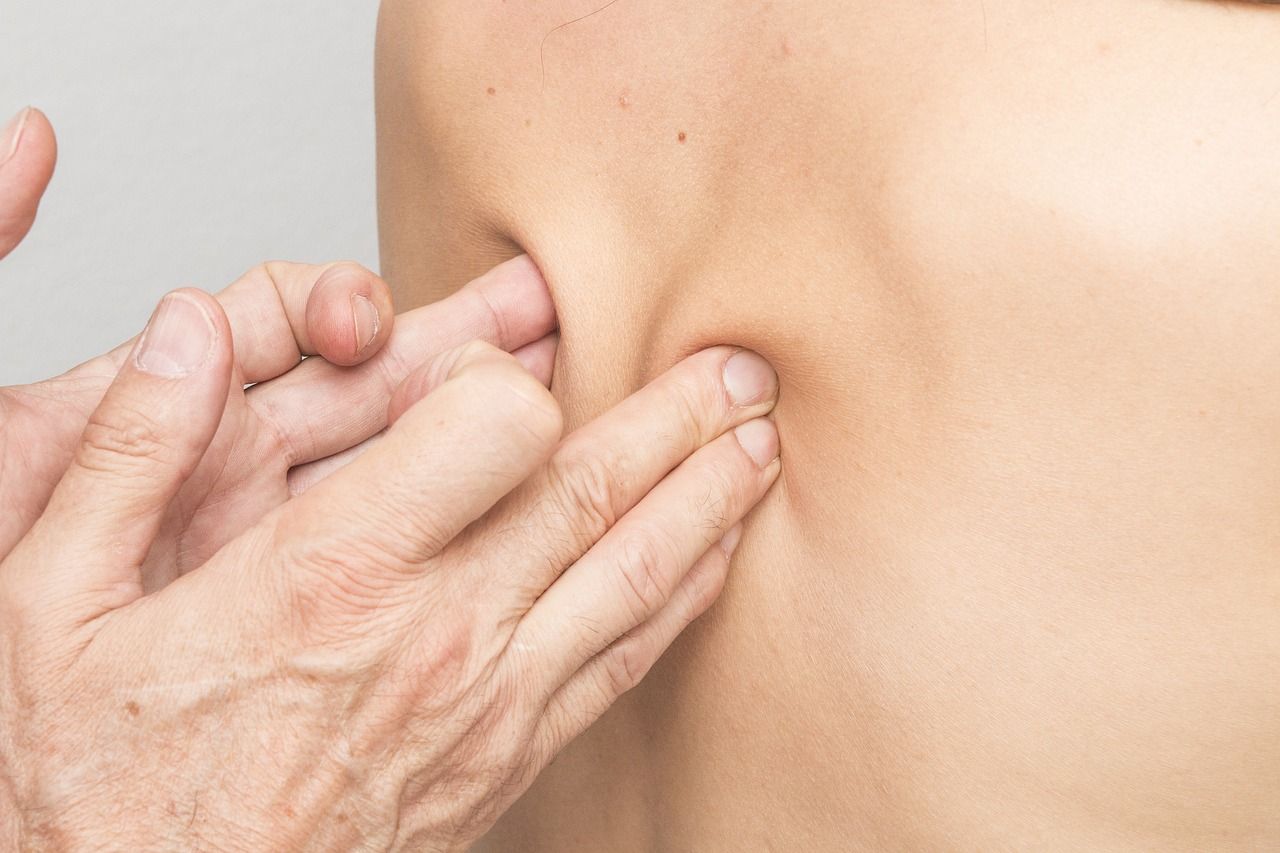 Hand pressing on a person’s back near the shoulder blade. Skin is visible, and hands are in focus.