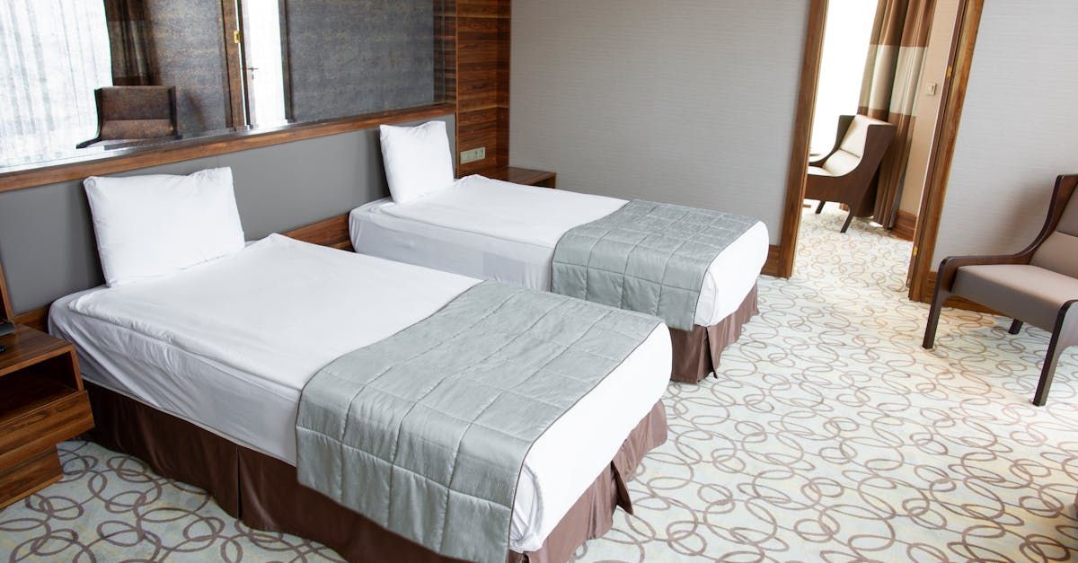 A hotel room with two beds and a chair.