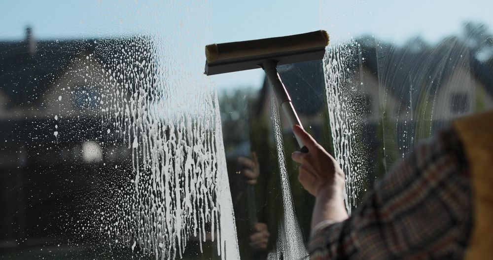 Hand wiping white window frame with a cloth during cleaning or painting