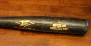 A black easton baseball bat is sitting on a wooden table.