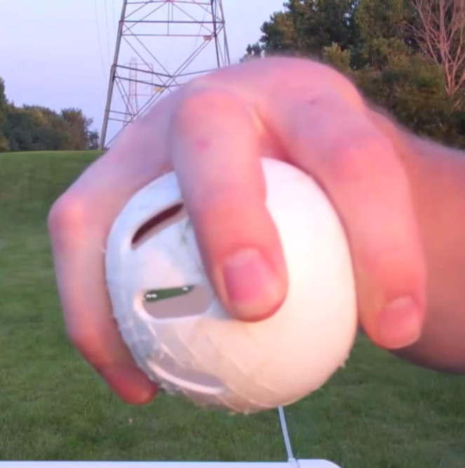 A person is holding a white ball in their hand