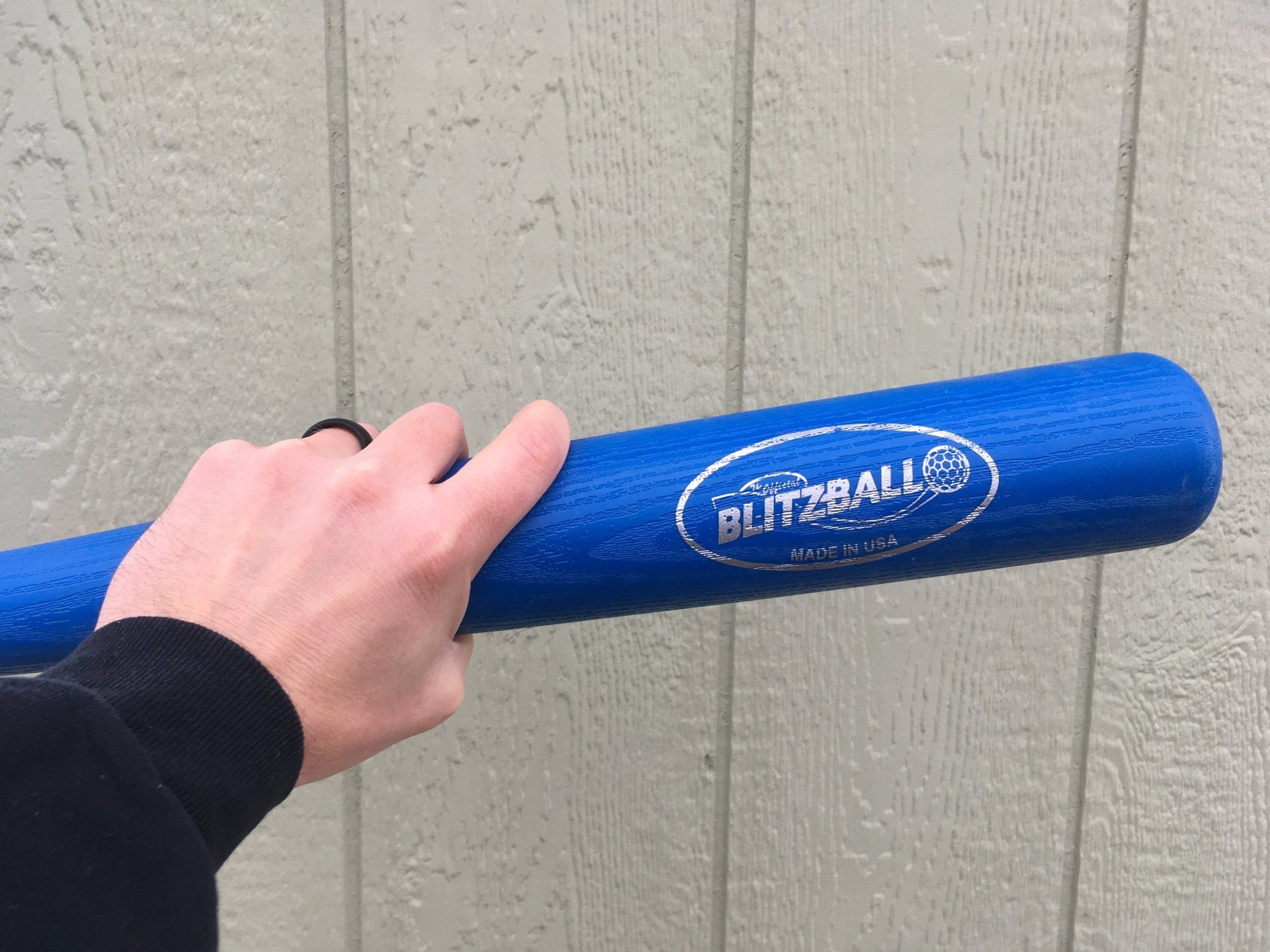 A person is holding a blue baseball bat in their hand.