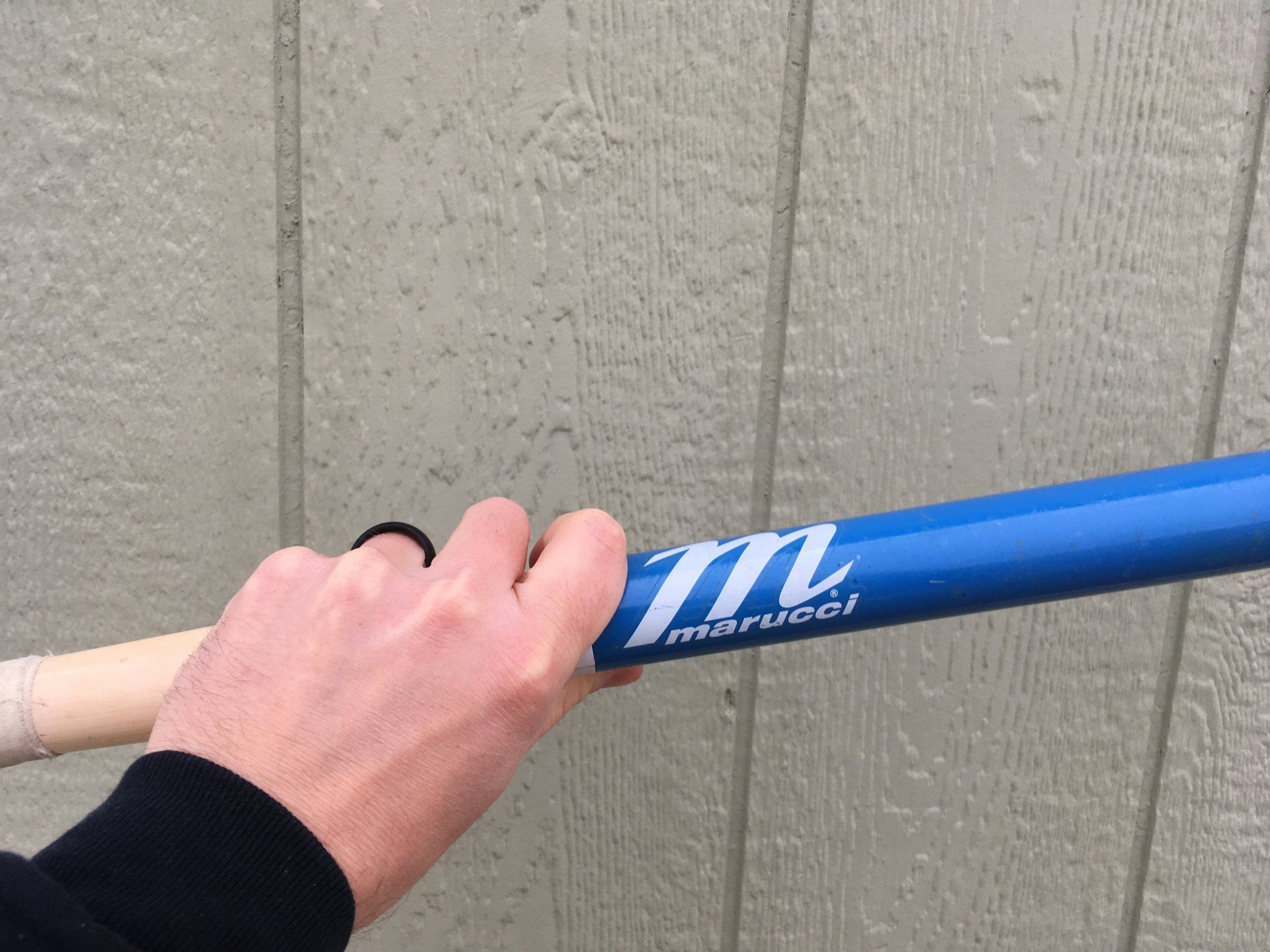 A person is holding a blue baseball bat in their hand.