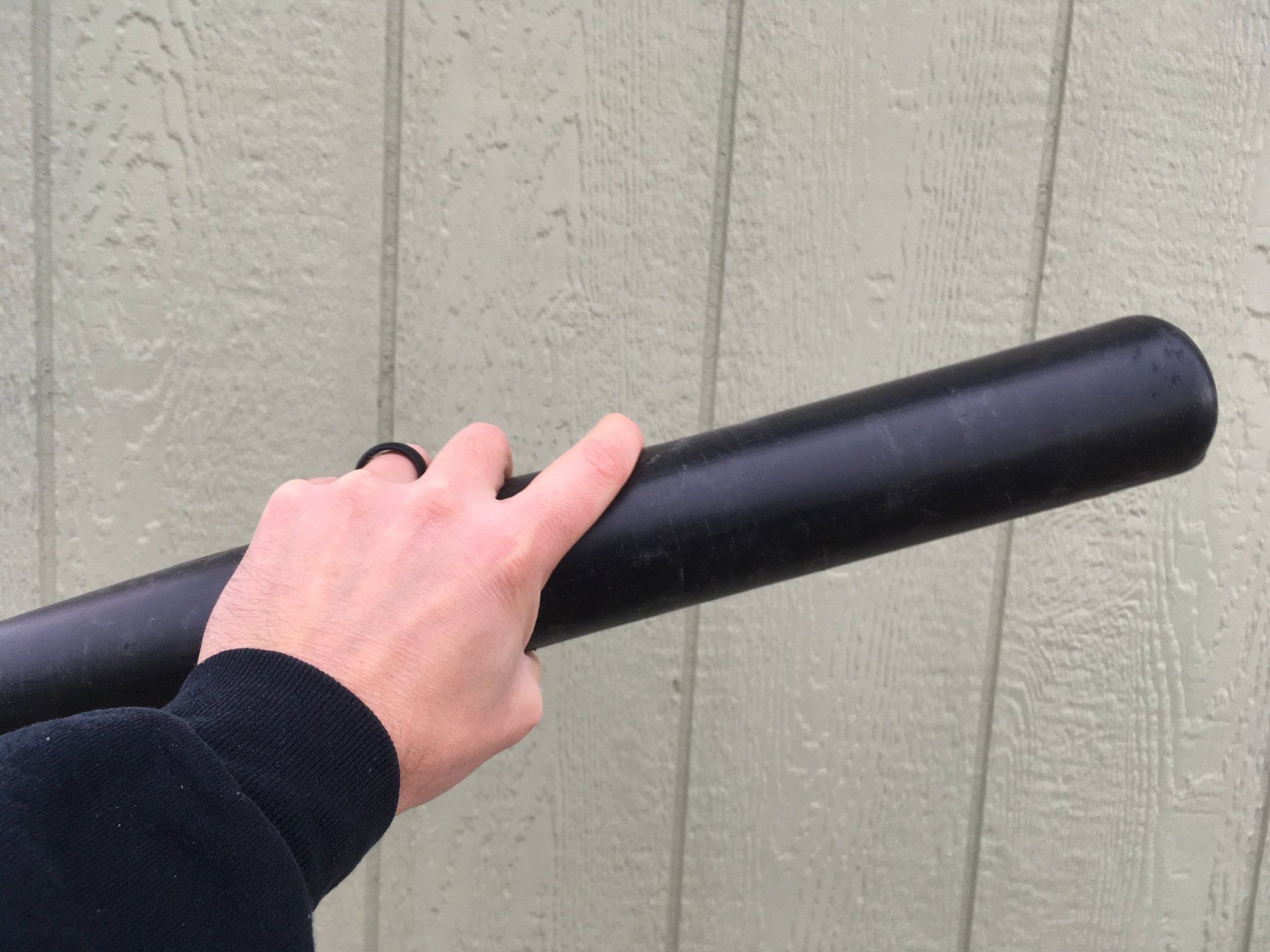 A person is holding a black baseball bat in their hand.