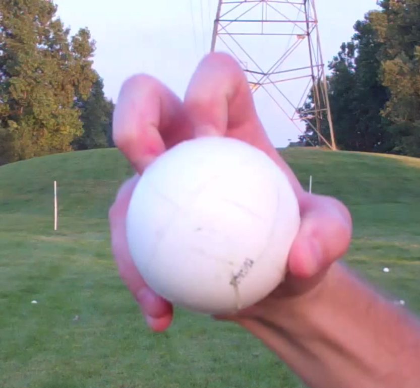 A person is holding a golf ball in their hand