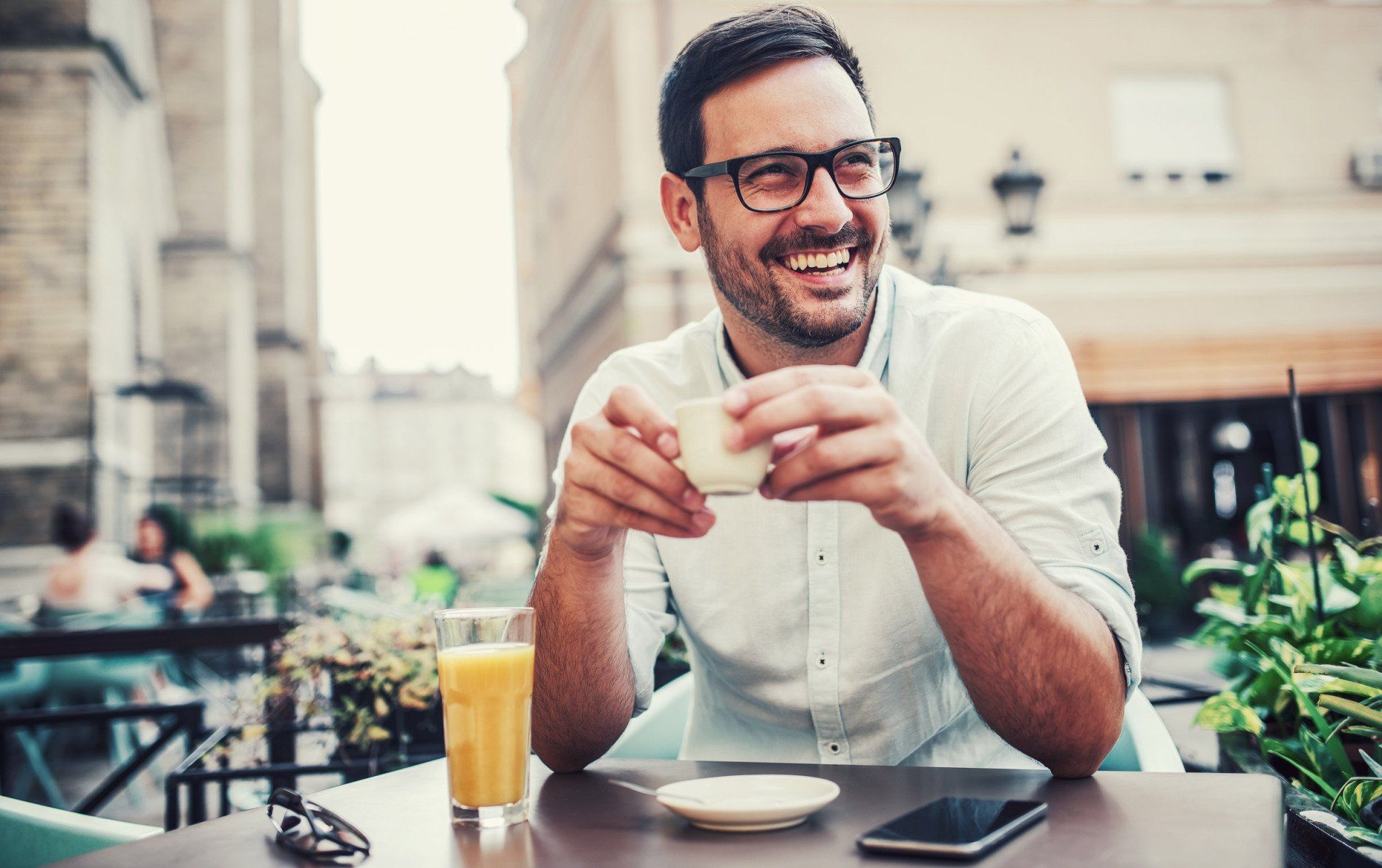 Man in glasses laughs while drinking coffee