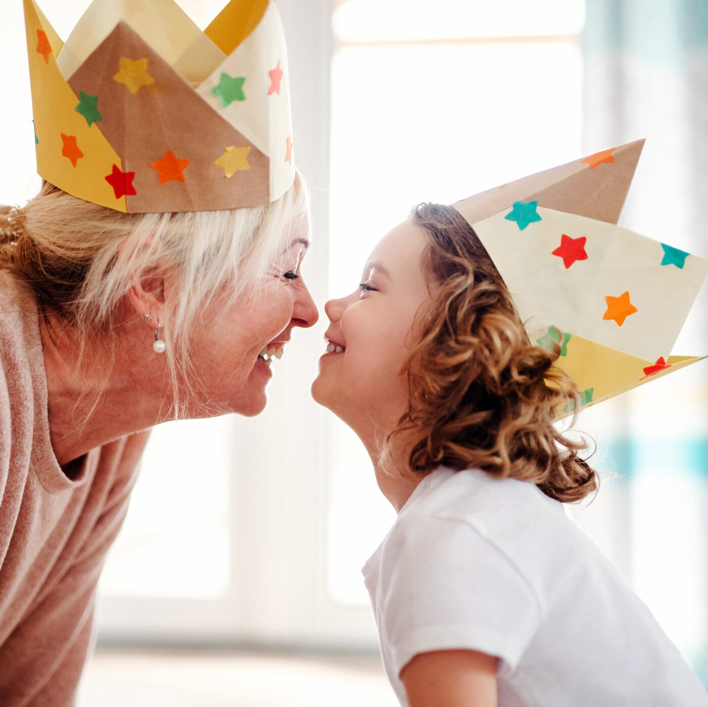 Older woman and child rubbing noses in birthday hats