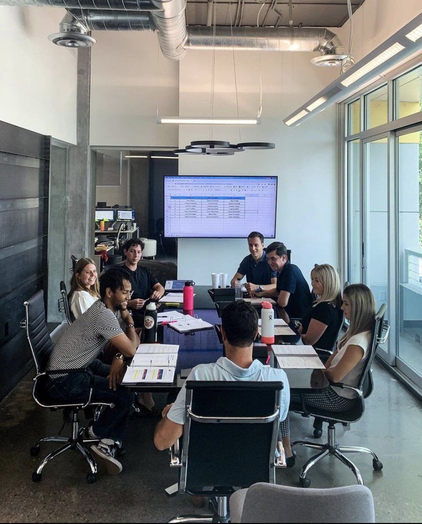 A group of people are sitting around a table in a conference room