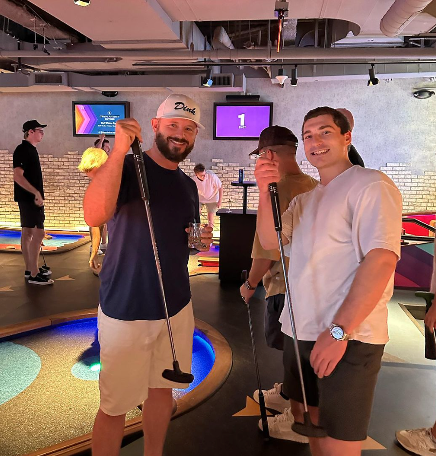 A man wearing a dodgers hat is holding a golf club