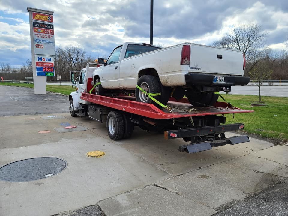 A white truck is being towed by a tow truck.