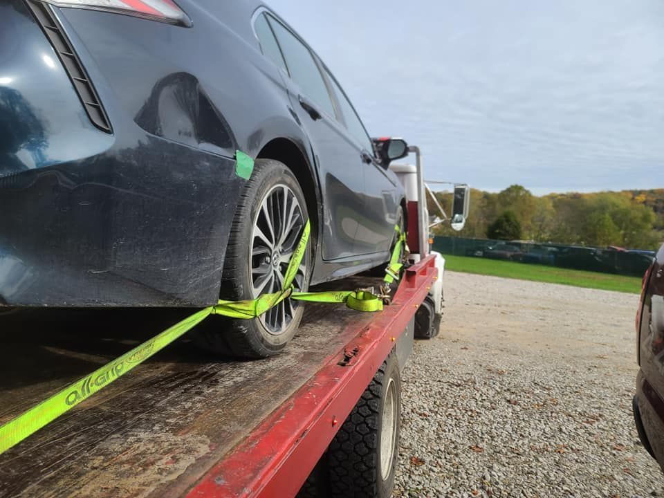 A black car is sitting on top of a red tow truck.