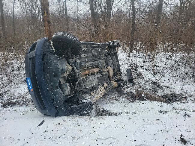 A car is laying on its side in the snow.