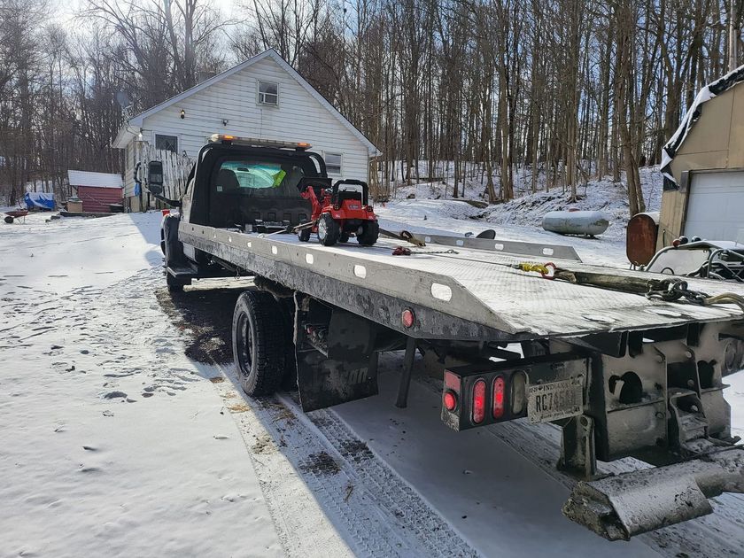 A tow truck is parked in the snow in front of a house.