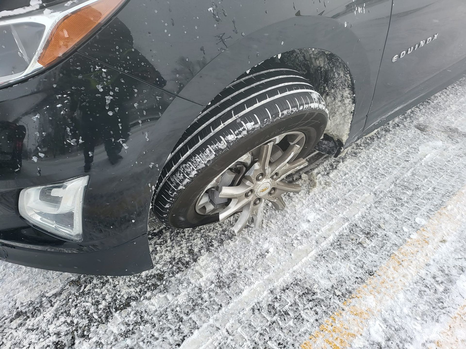 A black car is stuck in the snow on the side of the road