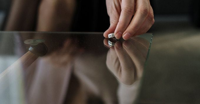 A woman is putting a ring on a glass table.