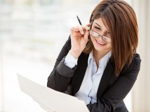 A woman wearing glasses is sitting in front of a laptop computer.