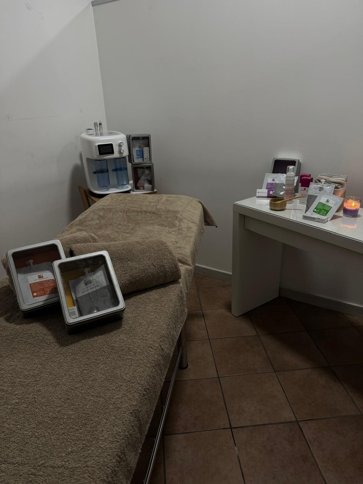 Sala trattamenti spa con lettino per massaggi, scrivania bianca e prodotti per la cura della pelle.