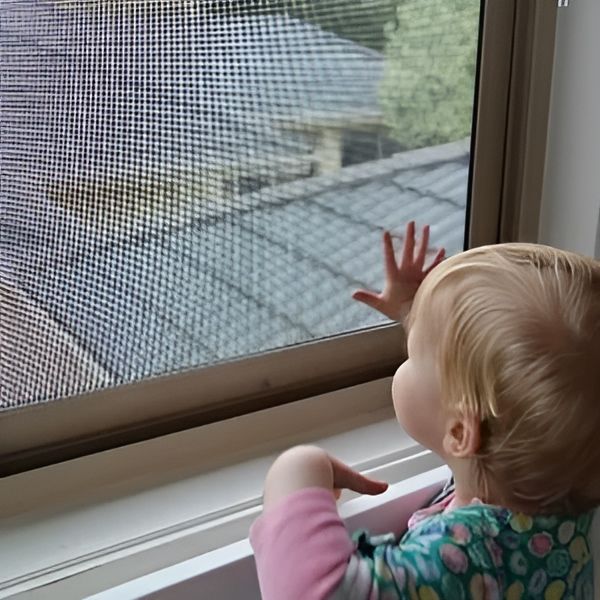 A Young Child With Blonde Hair Looks Out a Window — Cessnock Glass in Cessnock, NSW