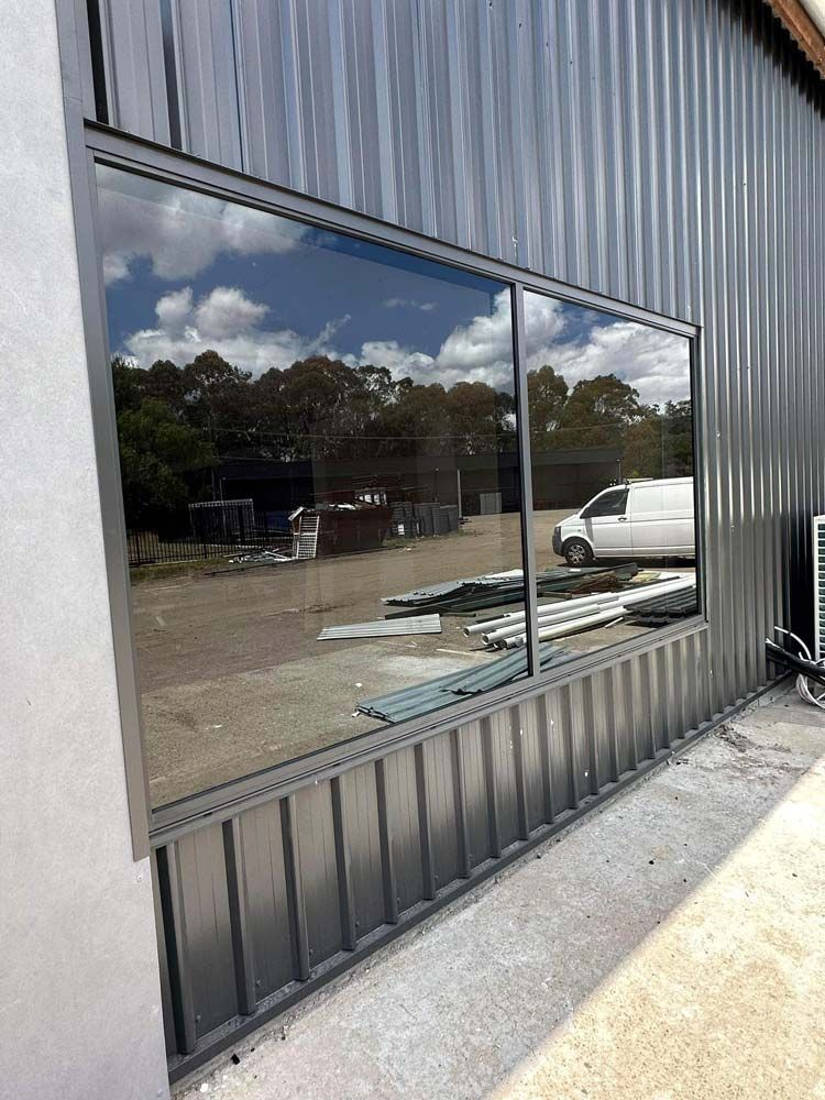 A Large Window on the Side of a Building With a Van Parked in Front of It — Cessnock Glass in Cessnock, NSW