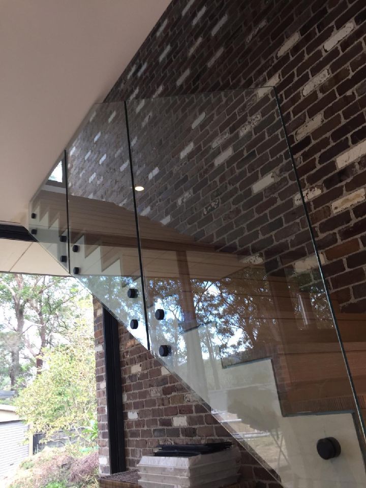 Glass Staircase With Black Hardware Against a Brick Wall — Cessnock Glass in Cessnock, NSW