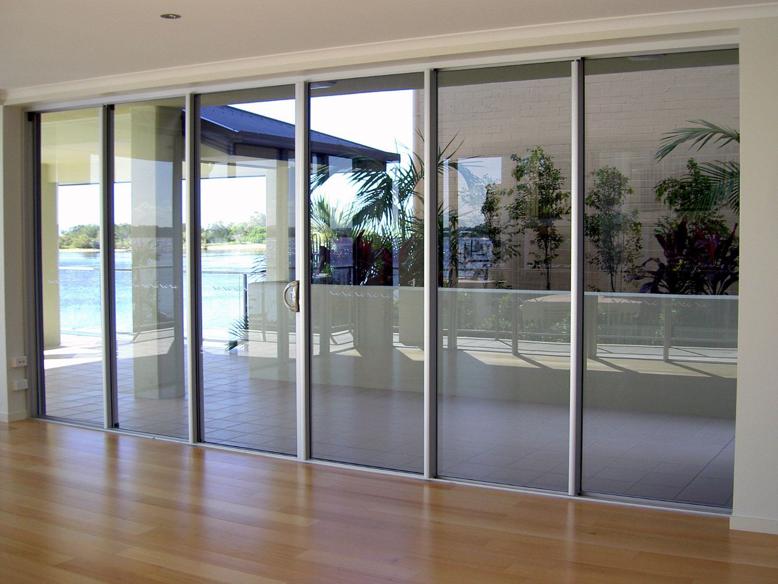 Glass sliding doors, open to a patio with a waterfront view, set in a modern home — Cessnock Glass in Cessnock, NSW