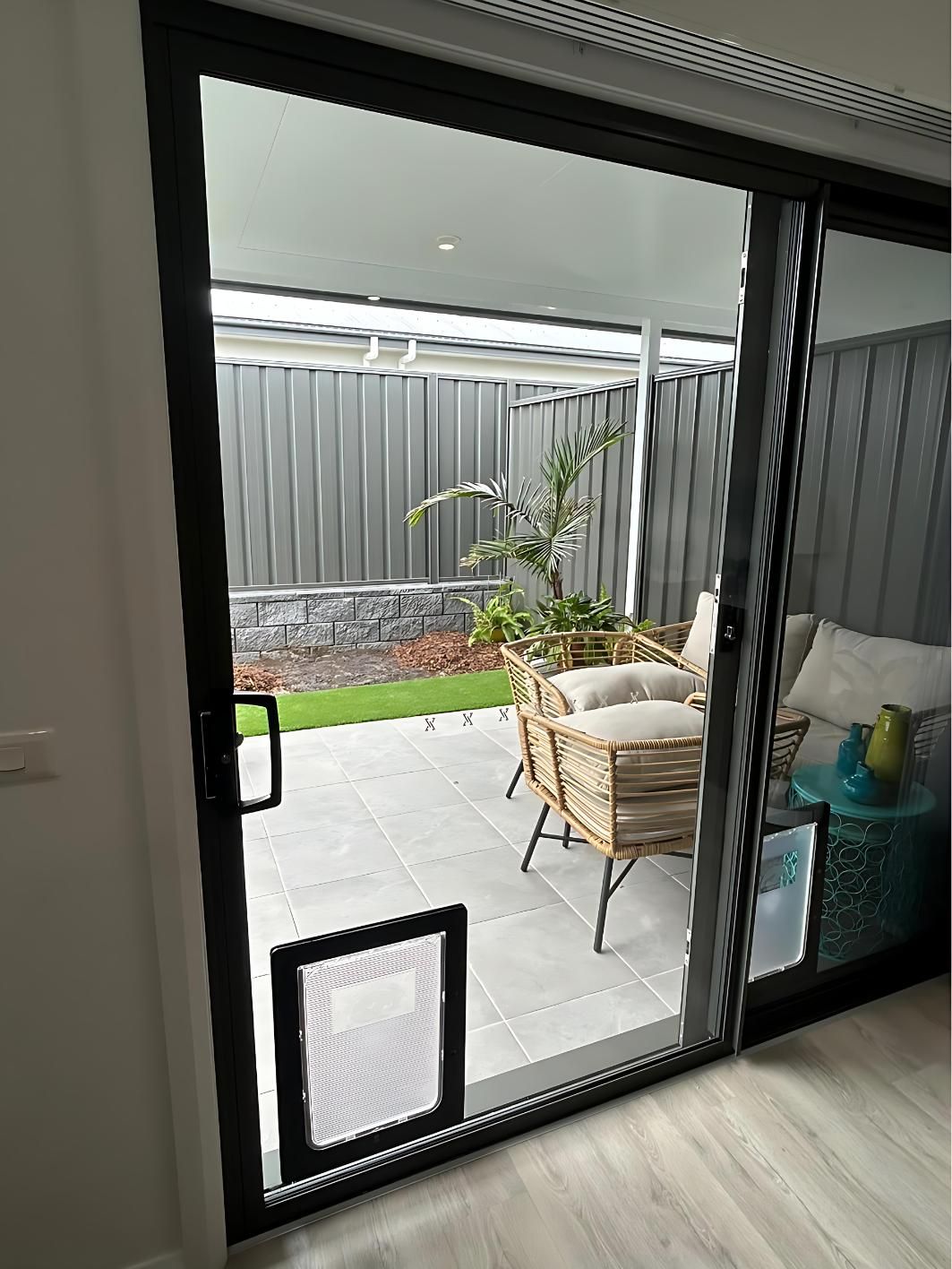 A Sliding Glass Door Leading to a Patio With a Dog Door — Cessnock Glass in Cessnock, NSW