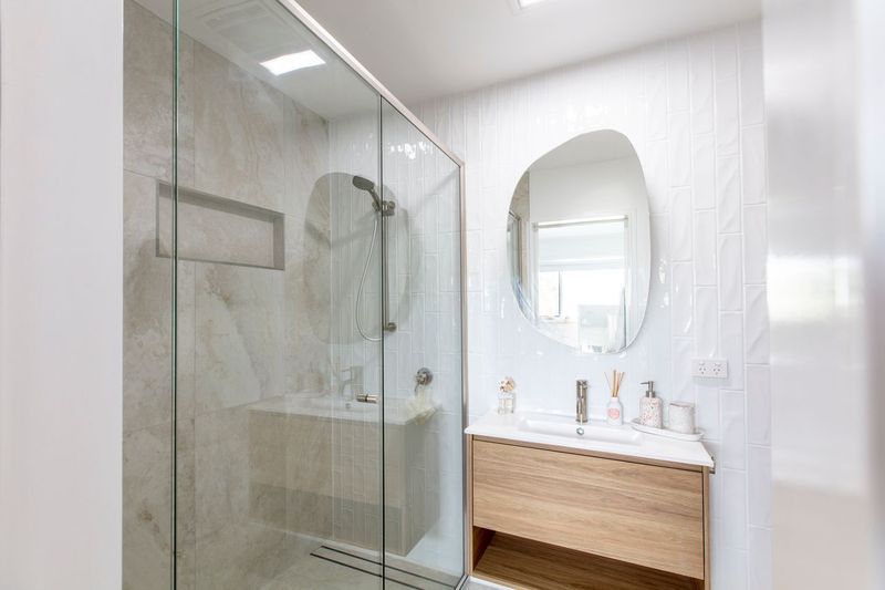 Modern bathroom with a glass shower, vanity, and abstract mirror — Cessnock Glass in Cessnock, NSW