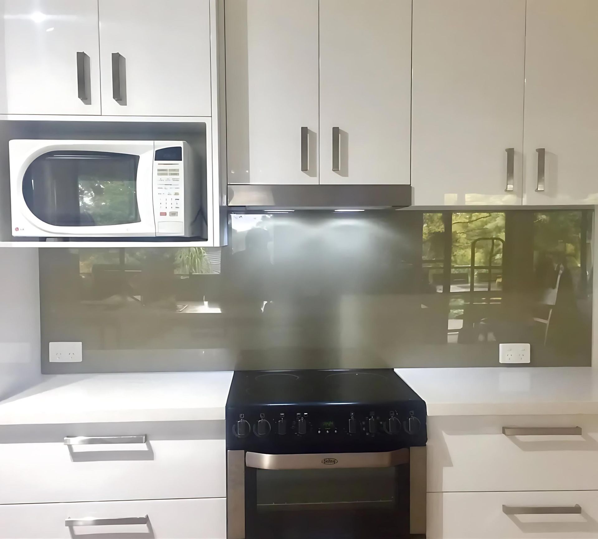 A Kitchen With White Cabinets and a Black Stove Top Oven — Cessnock Glass in Newcastle, NSW