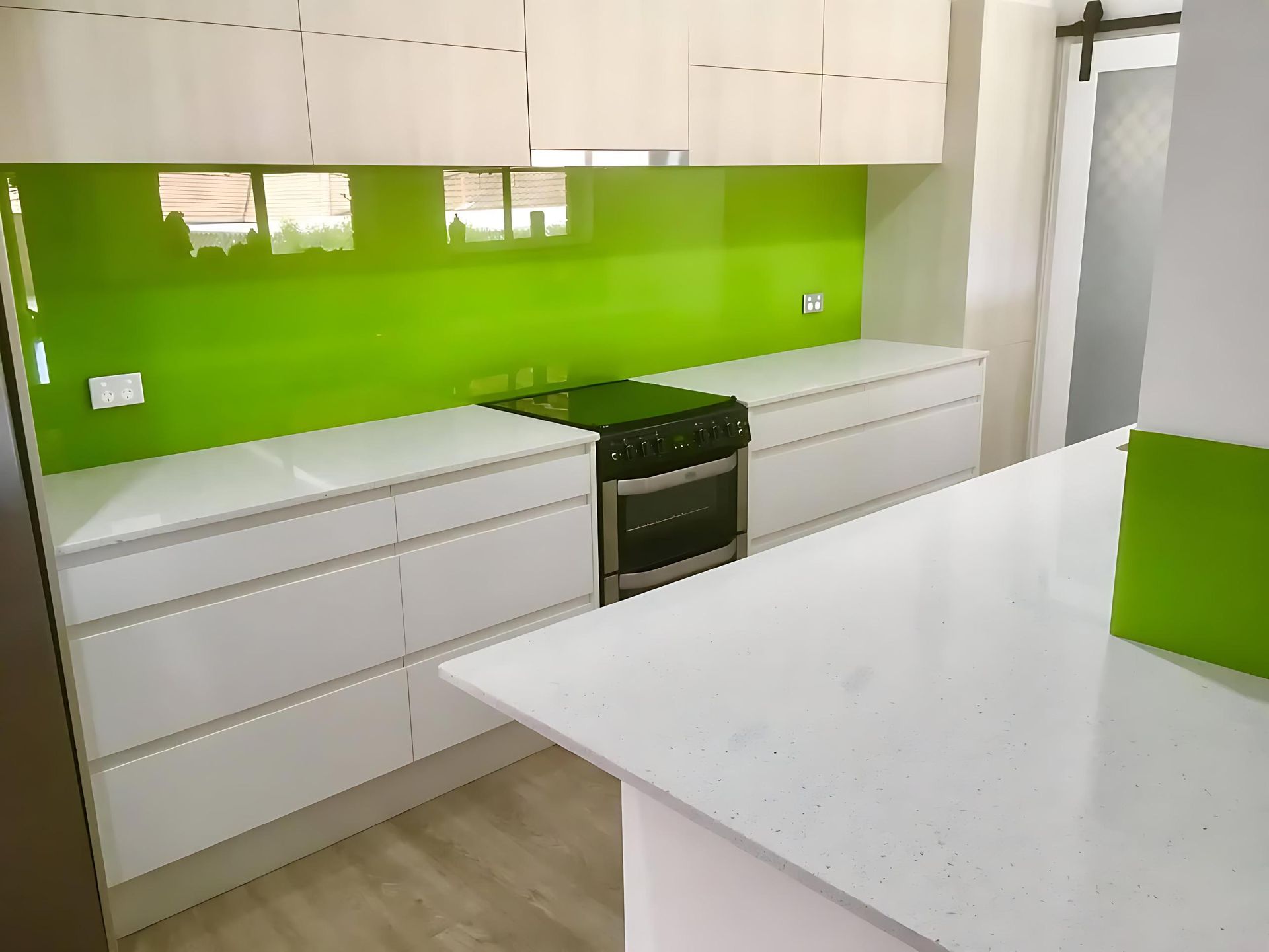 A Kitchen With a Green Backsplash and White Cabinets — Cessnock Glass in Central Coast, NSW
